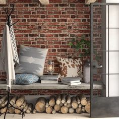 a brick wall with books, pillows and blankets next to firewood stacked on the floor