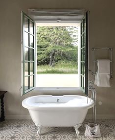 a bathtub sitting in front of an open window