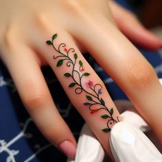 a woman's hand with a flower tattoo on her left thumb and the ring finger