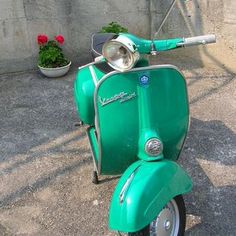 a green scooter parked next to a wall