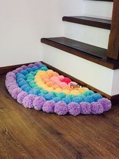 a rainbow rug sitting on the floor in front of a stair case next to a wooden banister