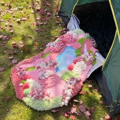 a blanket is laying on the ground next to a tent in the grass with leaves scattered around it