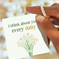 a person holding up a card that says i think about you every daisy