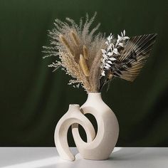 a white vase with some dried plants in it