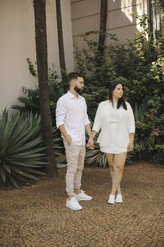 a man and woman standing next to each other holding hands