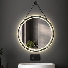 a bathroom sink with a round mirror on the wall above it and a potted plant