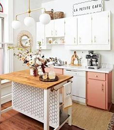 a kitchen with white cabinets and pink accents on the countertop, along with wooden floors