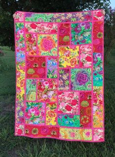 a pink and green patchwork quilt on grass