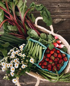 strawberries, radishes, daisies and other vegetables in a basket on a wooden table