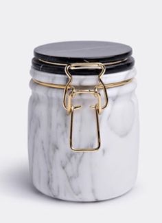 a marble jar with gold handles and a black lid is shown on a white background