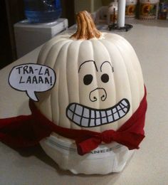 a white pumpkin with a face drawn on it and a red bow tie around its neck