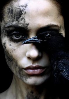 a woman with black makeup and a crow on her face