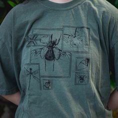 Screen Printed T-Shirt Each bug shirt is printed by hand in my own house. Its handmade nature makes each piece unique and imperfect, the shirts are not drop shipped.  On the shirt is a hand illustrated selections of bugs! The shirts are perfect for insect lovers to represent their love of beautiful bugs. All of the unisex shirts are soft, long lasting Comfort Color shirts. Interested in a custom color pairing? Don't hesitate to reach out and ask! Shipping can take up to 1-2 weeks depending on current stock. Check out my instagram :) @nat_orourke_art Vintage Hand-printed Relaxed Fit Top, Hand Printed Short Sleeve Graphic Tee, Nature-inspired Cotton Tops With Graphic Print, Casual Organic Cotton Tops With Custom Print, Nature-inspired Cotton Tops With Screen Print, Relaxed Fit Cotton Tops With Custom Artwork, Green Cotton Nature-inspired T-shirt, Nature-inspired Green Cotton T-shirt, Green Nature-inspired Cotton T-shirt