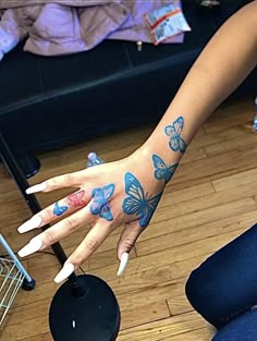 a woman's hand with blue butterflies painted on her left arm and the other hand