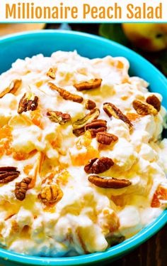 a bowl filled with whipped cream and pecans on top of a wooden table next to an apple