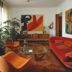 a living room filled with furniture and a painting on the wall above it's glass coffee table