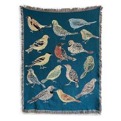 a blue blanket with birds on it and fringes hanging from the front, in various colors