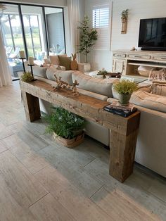 a living room filled with furniture and a flat screen tv on top of a wooden table