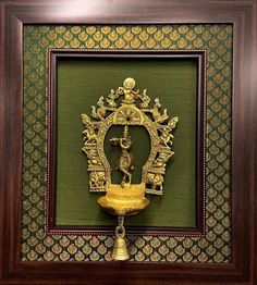 a gold statue in a wooden frame hanging on a wall next to a green wall