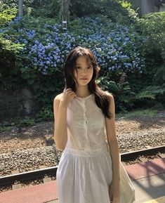 a young woman is standing on the train tracks