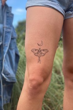 a woman's leg with a small tattoo of a moth on the left side