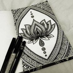 some pens are sitting on top of a paper with an intricate flower design in the middle