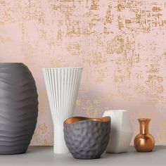 three different vases sitting on top of a table next to each other in front of a pink wall