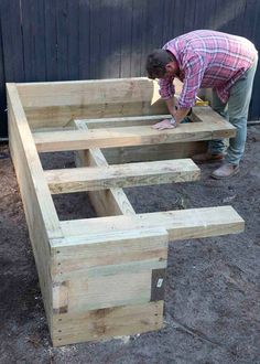 a man is working on some kind of bench made out of pallet wood and plywood