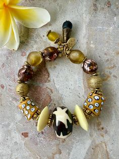 Bold African-inspired bracelet features a striking mix of large, textured beads in earthy tones, including amber, black, and ivory tones, adorned with intricate patterns and gold accents. The central bead showcases a carved star design, while other beads display dots and natural stone-like swirls, creating a statement piece that exudes a rich, tribal aesthetic. This bracelet is made up on stretch elastic, to fit a adult wrist size  8-10-12 African Trade Bead Jewelry, African Beaded Bracelets, African Trade Beads, Star Design, Trade Beads, Bracelet Crafts, Etsy Jewelry