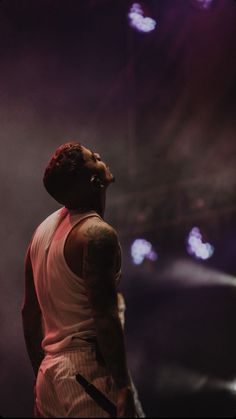 a man standing in front of a stage with his head turned to the side and lights behind him