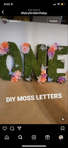 the word one is made out of fake grass and pink flowers on top of it