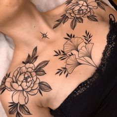 a woman laying on top of a bed with tattoos on her chest and flowers in the middle