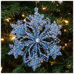 a blue snowflake ornament hanging from a christmas tree