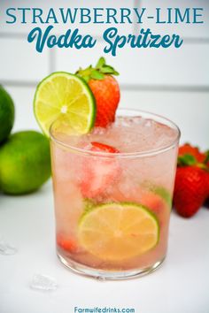 strawberry lime vodka spritzer in a glass with strawberries and limes on the side