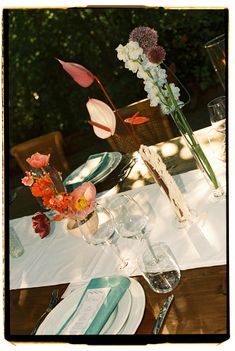 the table is set with flowers and plates