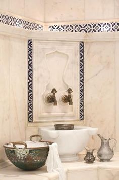 a white sink sitting under a bathroom faucet next to a bowl filled with water