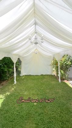 a large white tent with chandelier and grass