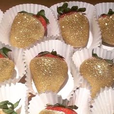 some strawberries with gold glitter on them are arranged in white paper wrappers and placed next to each other