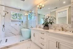 a large bathroom with marble counter tops and white cabinets, along with a walk in shower