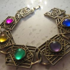 Adorable old vintage square cut gold tone bracelet 7 1/2 Inches in Length with a Snap Lock Closure. Pretty Colored Oval colors of hot pink, yellow, green, purple and blue plastic are just so pretty. Lovely dark gold link bracelet - no marking I can see on this bracelet. FREE SHIPPING - GIFT WRAPPED - 10% OFF AT CHECKOUT. Adjustable Multicolor Vintage Cuff Bracelet, Vintage Multicolor Bangle Bracelets, Gold-tone Oval Link Charm Bracelet, Vintage Multicolor Cabochon Bracelets, Vintage Hallmarked Gold Link Bracelet, Lucite Bracelets, Gold Link Bracelet, Pale Gold, Square Cut