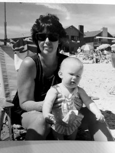 a woman holding a baby on the beach