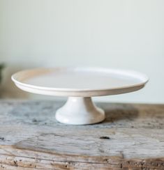 a white cake plate sitting on top of a wooden table