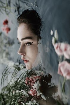 a woman with flowers in her hair and water on her face, looking off to the side