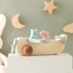 a wooden toy boat with two bears in it and stars on the wall behind it