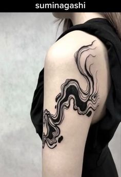 a woman's arm with a black and white tattoo design on the left shoulder