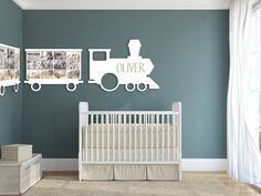 a baby's room with a train wall decal and pictures on the wall