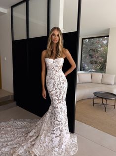 a woman standing in front of a black door wearing a white dress with flowers on it