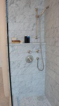 a walk in shower sitting next to a white tiled wall and floor covered in marble