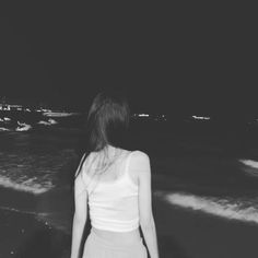 a woman standing on the beach at night