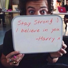 a man holding up a sign that says stay strong i believe in you harry x